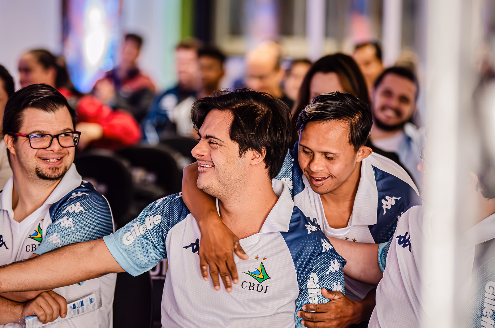Atletas da delegação de futsal inclusivo comemoram abraçados, no meio da plateia do Summit.