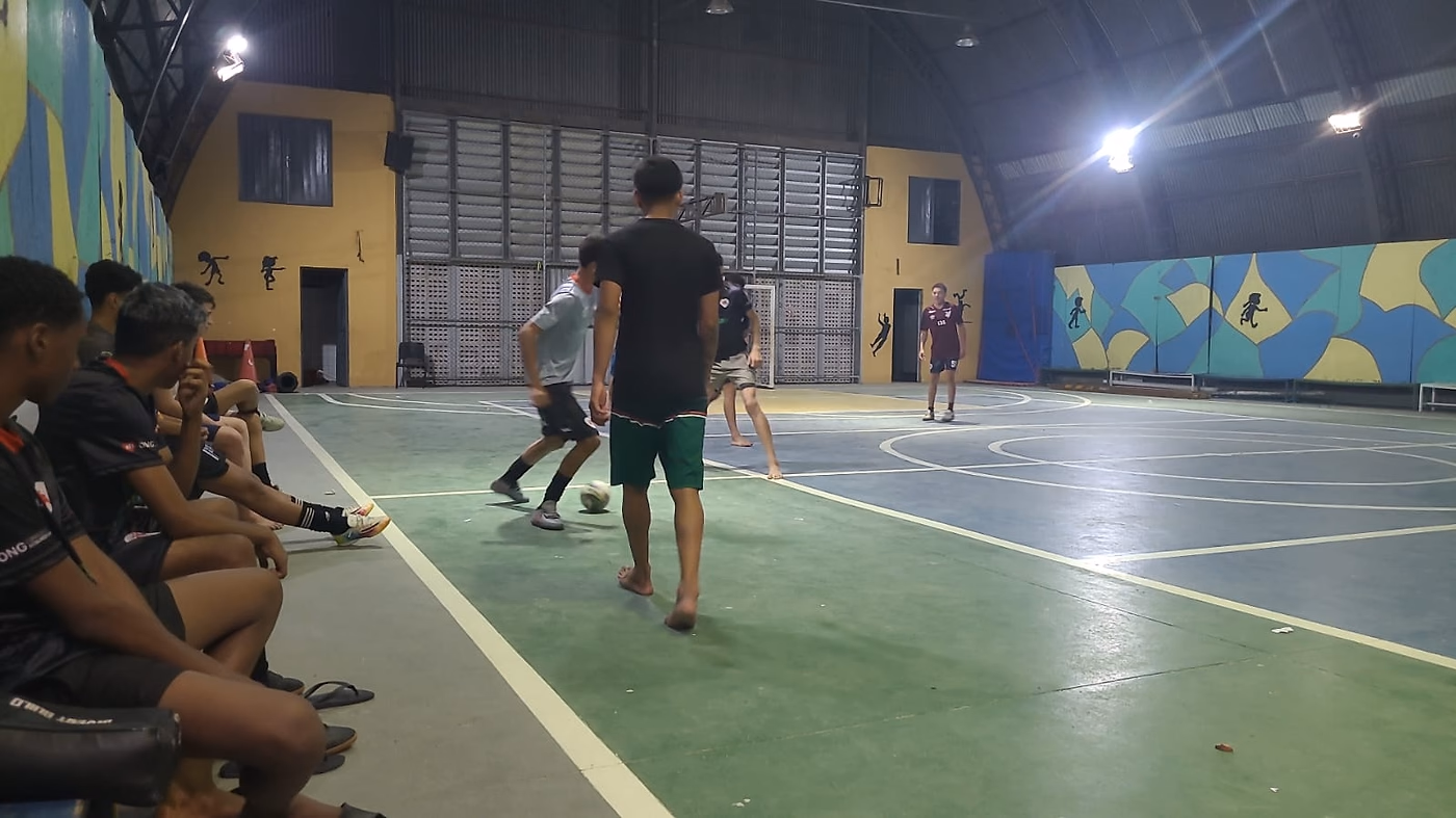 Grupo sentado na lateral acompanha a partida enquanto os outros jogam.