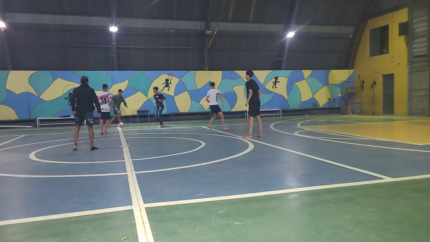 Atividade em andamento na quadra coberta, com os adolescentes espalhados pelo espaço.