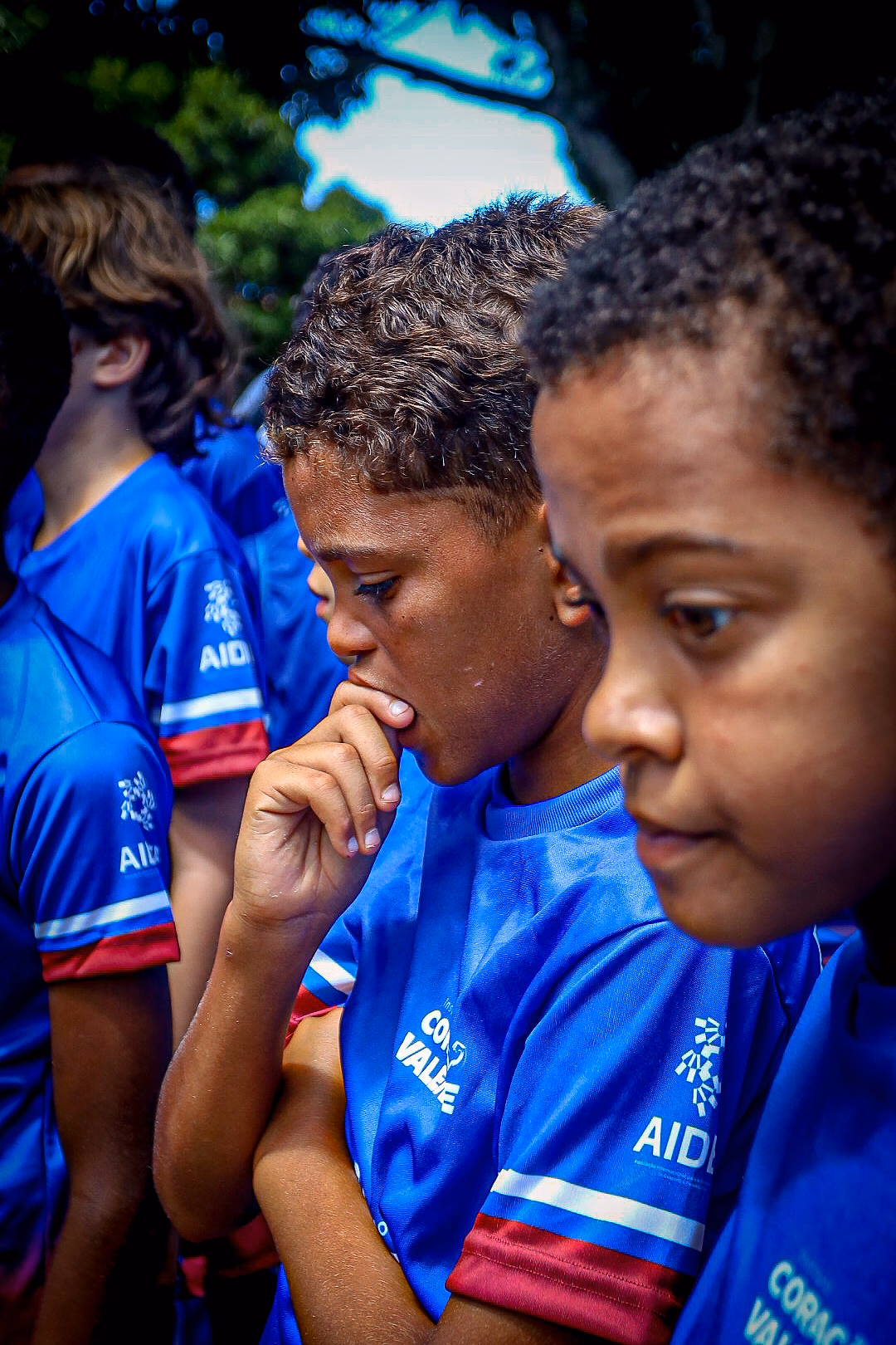 Dois meninos de uniforme azul acompanham a atividade com atenção, lado a lado.