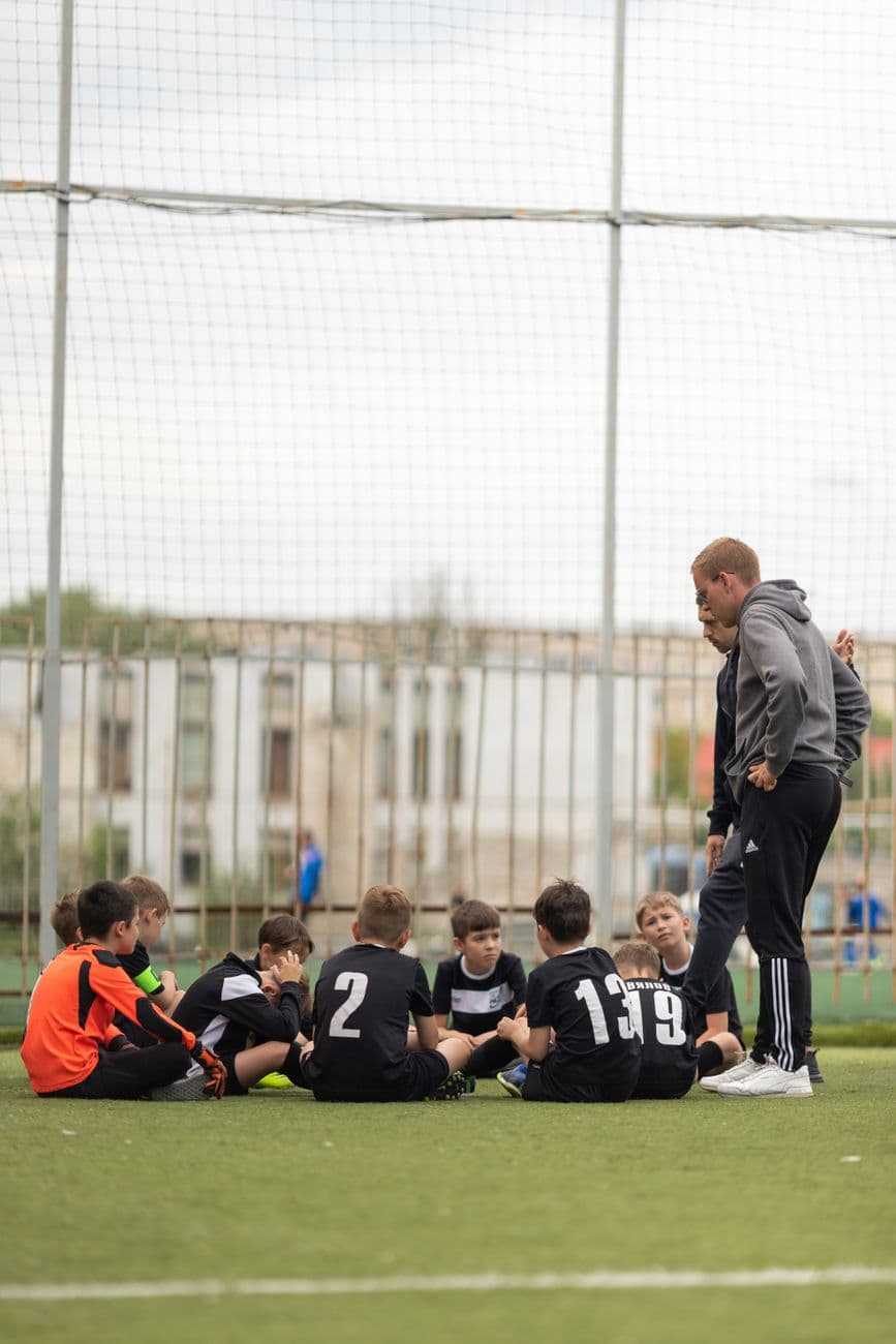 Treinador conversando com crianças antes do treino